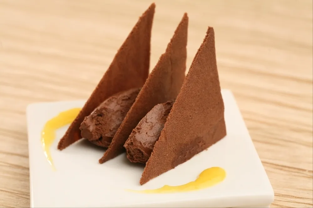 Image recette Tuiles au cacao, mousse choco-passion et coulis de jus de mangue.